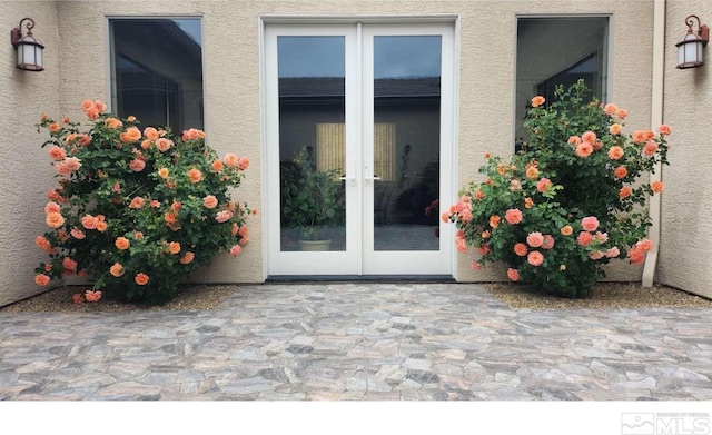 entrance to property featuring a patio area, french doors, and stucco siding