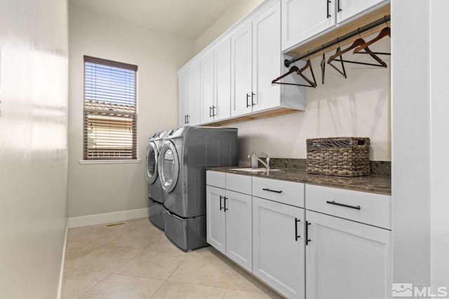 laundry room featuring light tile patterned floors, baseboards, cabinet space, a sink, and washing machine and dryer