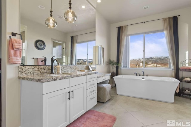 full bathroom featuring tile patterned flooring, a healthy amount of sunlight, a freestanding bath, and vanity