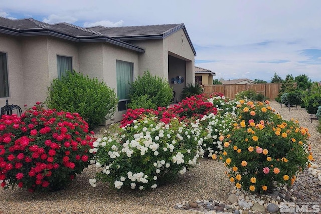 view of side of property featuring stucco siding and fence