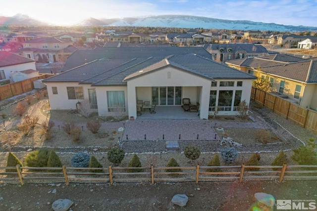 rear view of property with a patio, a fenced backyard, a residential view, a tiled roof, and a mountain view