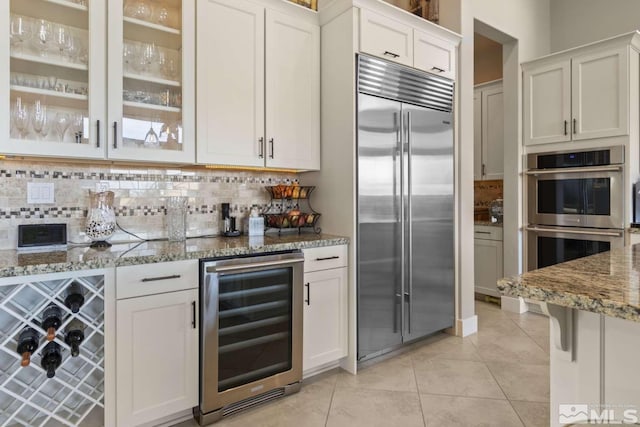 kitchen with light tile patterned floors, stainless steel appliances, tasteful backsplash, and beverage cooler