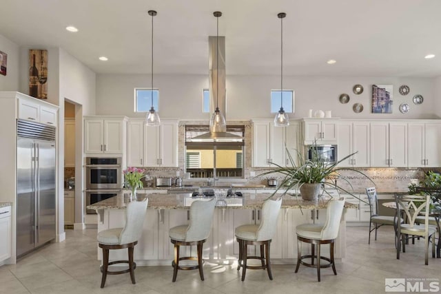 kitchen featuring light stone counters, tasteful backsplash, appliances with stainless steel finishes, and a center island