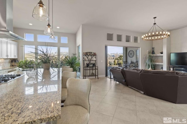 interior space with baseboards, light tile patterned floors, recessed lighting, an inviting chandelier, and a towering ceiling