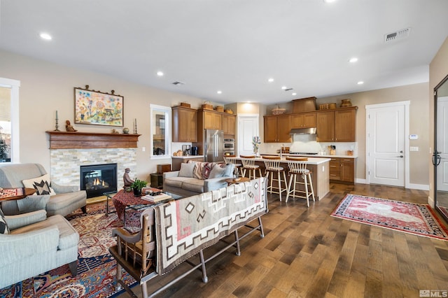 living area with visible vents, recessed lighting, a fireplace, baseboards, and dark wood-style flooring