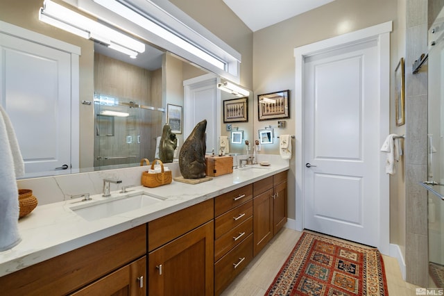 bathroom featuring double vanity, a stall shower, and a sink