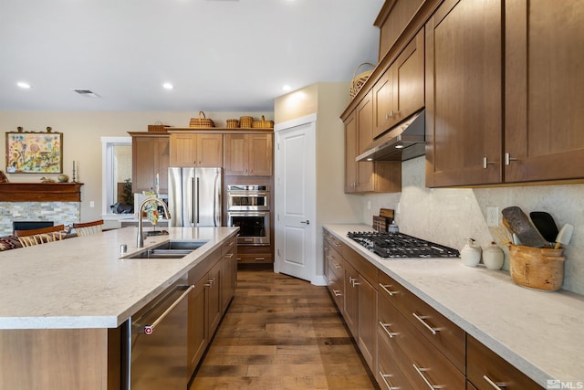 kitchen with dark wood finished floors, a sink, stainless steel appliances, light countertops, and under cabinet range hood