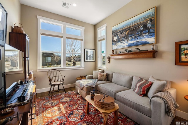 living room with visible vents, baseboards, and wood finished floors