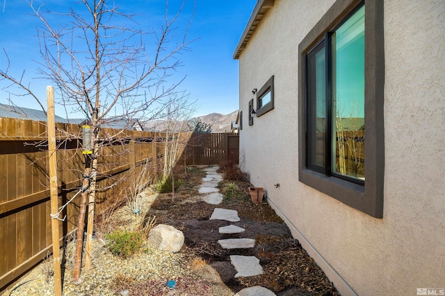 view of property exterior featuring stucco siding, a mountain view, and a fenced backyard