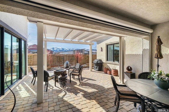 view of patio featuring fence, an outdoor fire pit, a grill, a mountain view, and a pergola