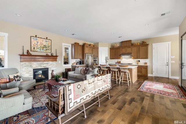 living area featuring visible vents, recessed lighting, a fireplace, and dark wood-style flooring