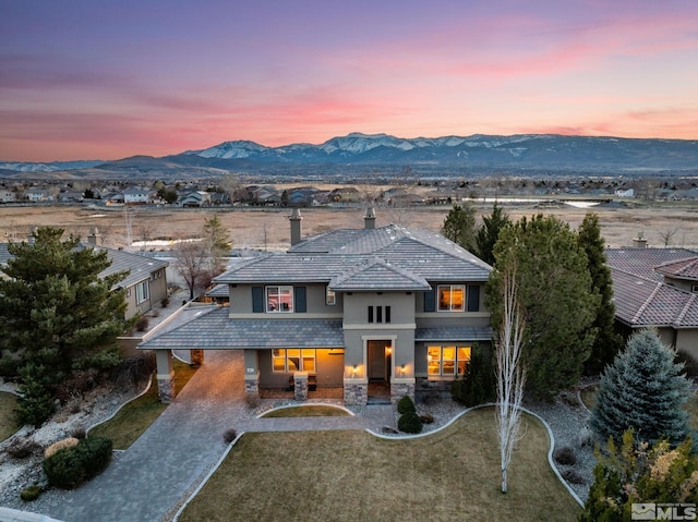 view of front facade with decorative driveway, a tile roof, a mountain view, and stucco siding