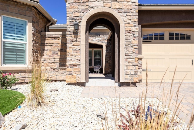 property entrance with stone siding and a garage