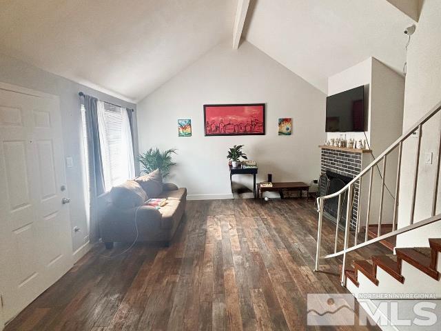 living room featuring a fireplace, vaulted ceiling with beams, hardwood / wood-style floors, and stairs