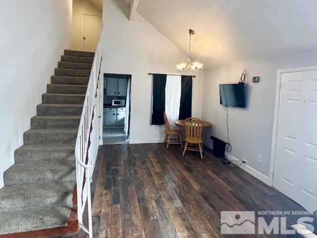 interior space featuring high vaulted ceiling, wood finished floors, baseboards, and a chandelier