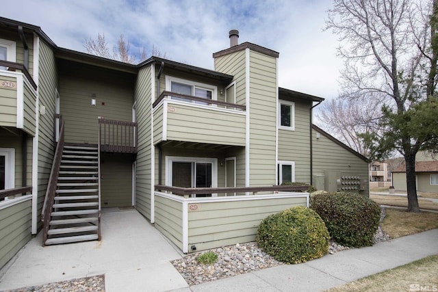 exterior space with stairs, a balcony, and a chimney