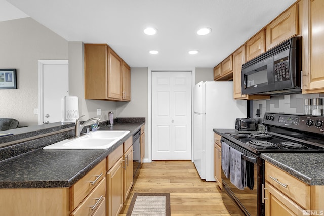 kitchen with light wood finished floors, dark countertops, recessed lighting, black appliances, and a sink