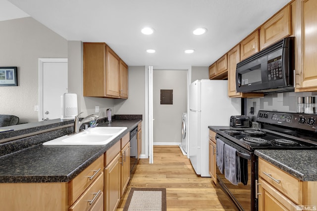 kitchen featuring light wood finished floors, dark countertops, washer / dryer, black appliances, and a sink