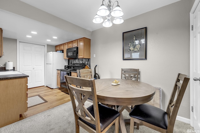 dining area with an inviting chandelier, recessed lighting, light colored carpet, and light wood finished floors