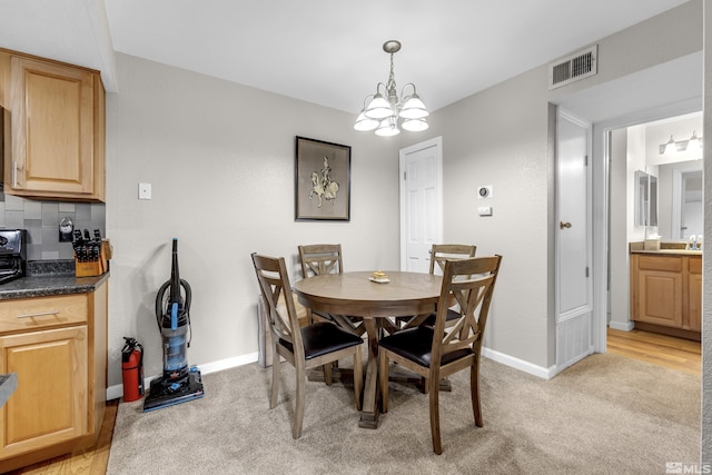 dining room featuring visible vents, light carpet, a notable chandelier, and baseboards