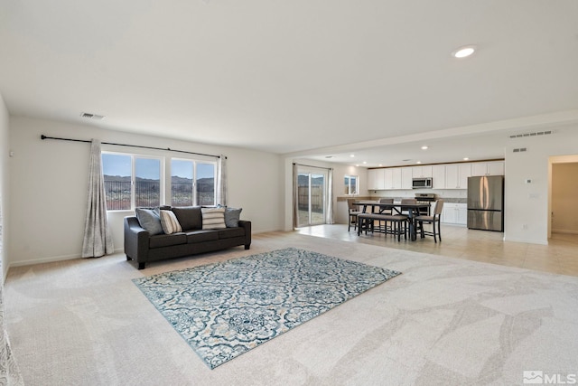 living room featuring recessed lighting, visible vents, baseboards, and light colored carpet