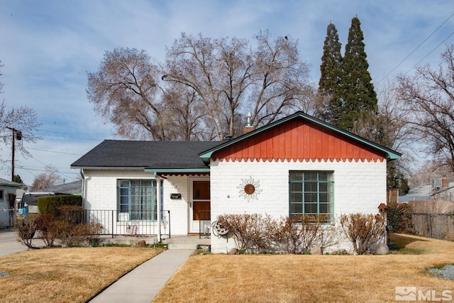 view of front of home with brick siding, a porch, a front yard, and fence