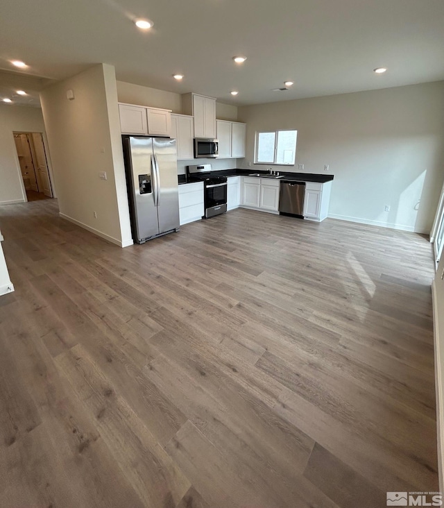 kitchen featuring light wood-style floors, stainless steel appliances, dark countertops, and white cabinets