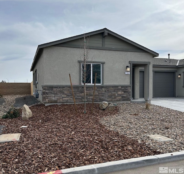 view of side of property featuring concrete driveway, an attached garage, stone siding, and stucco siding