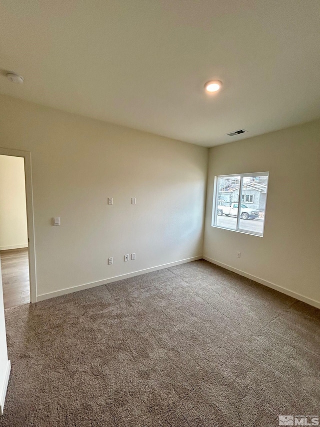 carpeted spare room with visible vents and baseboards