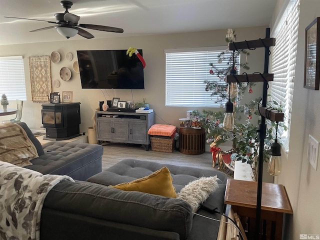 living area featuring wood finished floors, ceiling fan, and a wood stove