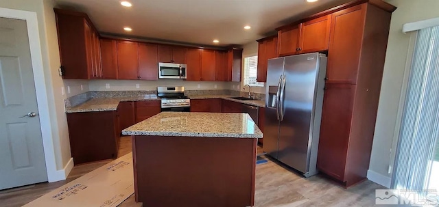 kitchen featuring a sink, a kitchen island, recessed lighting, appliances with stainless steel finishes, and light stone countertops