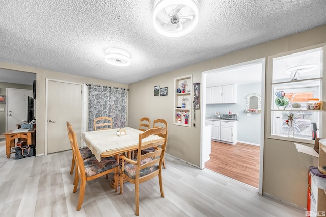 dining area featuring a textured ceiling, light wood-style flooring, and a toaster