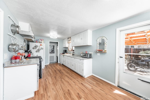 kitchen featuring range with gas stovetop, light wood-style floors, white cabinets, and light countertops