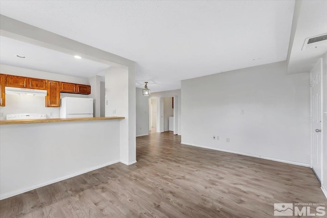 unfurnished living room featuring visible vents, wood finished floors, and baseboards