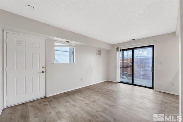 spare room with a textured ceiling, baseboards, and wood finished floors