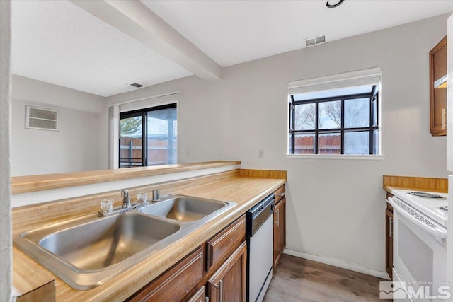 kitchen featuring white appliances, light wood-type flooring, visible vents, and a sink