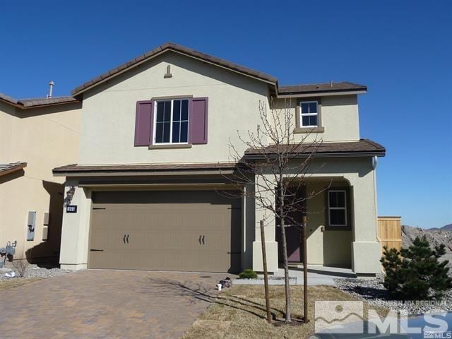 traditional-style home with stucco siding, an attached garage, and decorative driveway