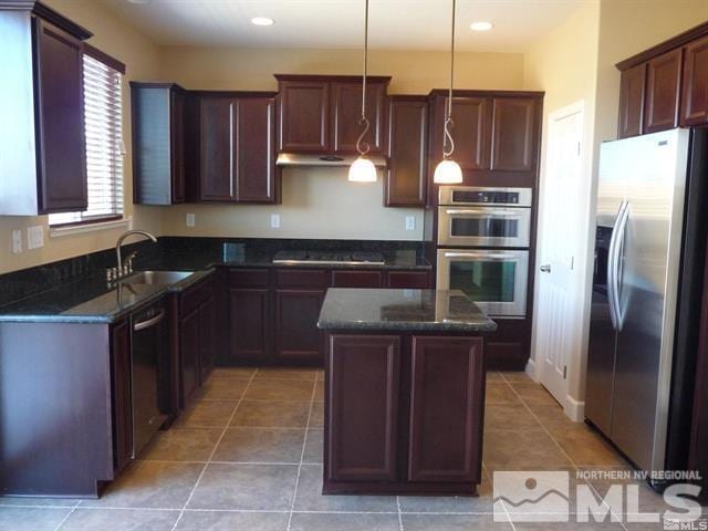 kitchen featuring a sink, appliances with stainless steel finishes, dark stone countertops, and hanging light fixtures