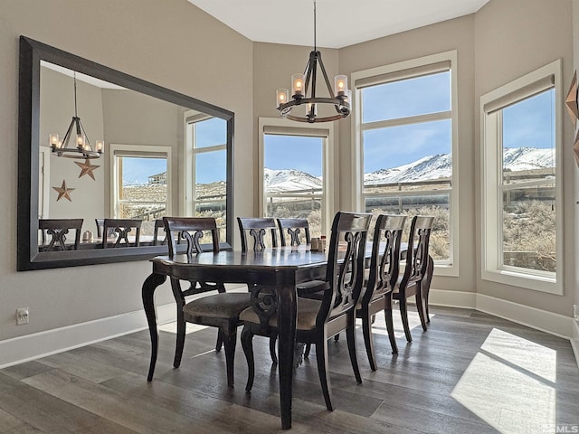 dining room featuring a chandelier, dark wood-style floors, a mountain view, and baseboards