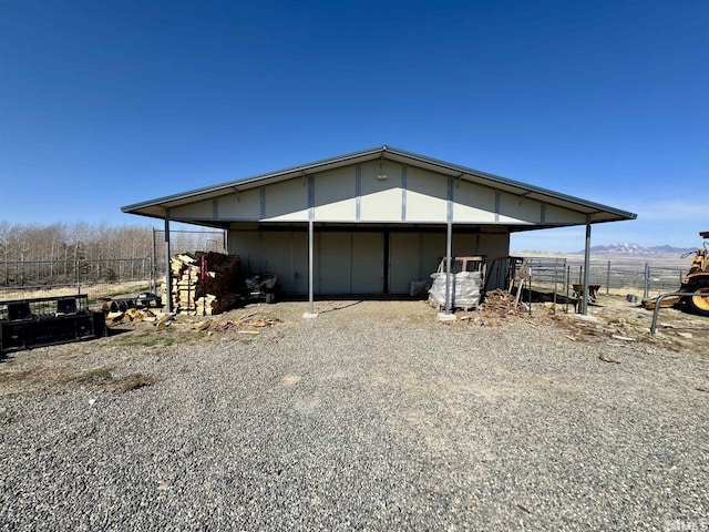 view of outdoor structure with gravel driveway, an outdoor structure, an attached carport, and an exterior structure