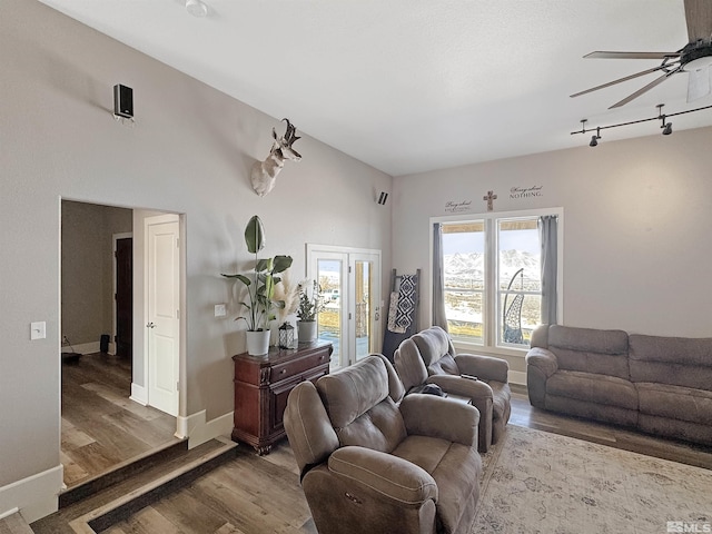 living room with track lighting, a ceiling fan, baseboards, and wood finished floors