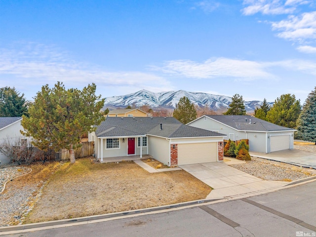 ranch-style house with fence, a mountain view, an attached garage, concrete driveway, and brick siding