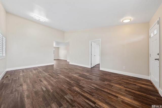 unfurnished room with dark wood-style floors, visible vents, and baseboards