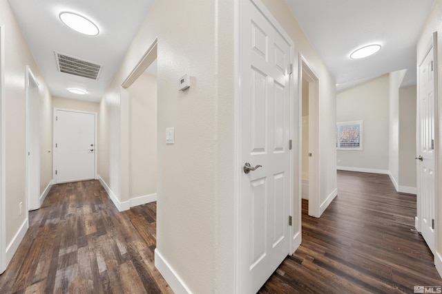 corridor featuring visible vents, baseboards, and dark wood-style floors