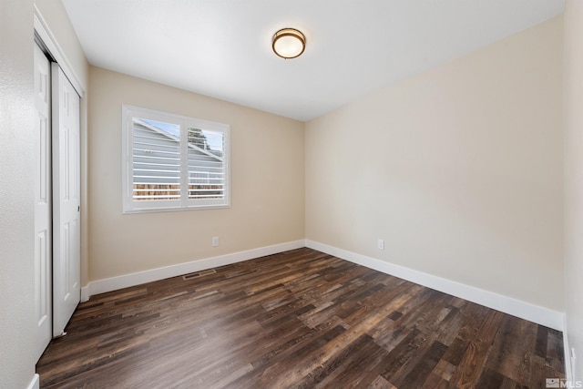 unfurnished bedroom with a closet, baseboards, and dark wood-style floors