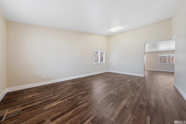 unfurnished room with visible vents, dark wood-style floors, and baseboards