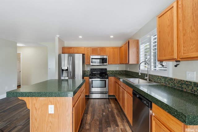 kitchen with dark countertops, dark wood-style floors, appliances with stainless steel finishes, and a sink