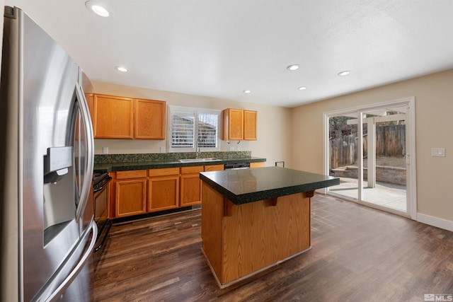 kitchen with dark wood-style floors, stainless steel fridge, a kitchen island, and a sink