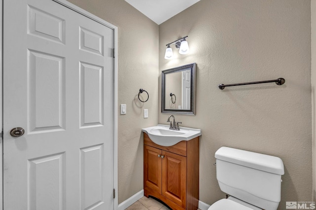 bathroom featuring baseboards, toilet, vanity, and tile patterned flooring