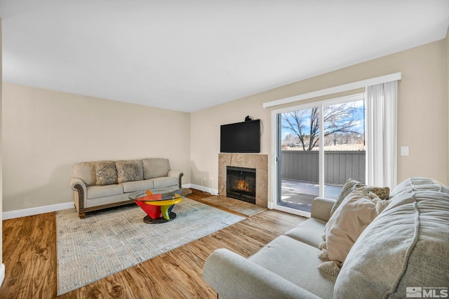 living room with a tiled fireplace, wood finished floors, and baseboards